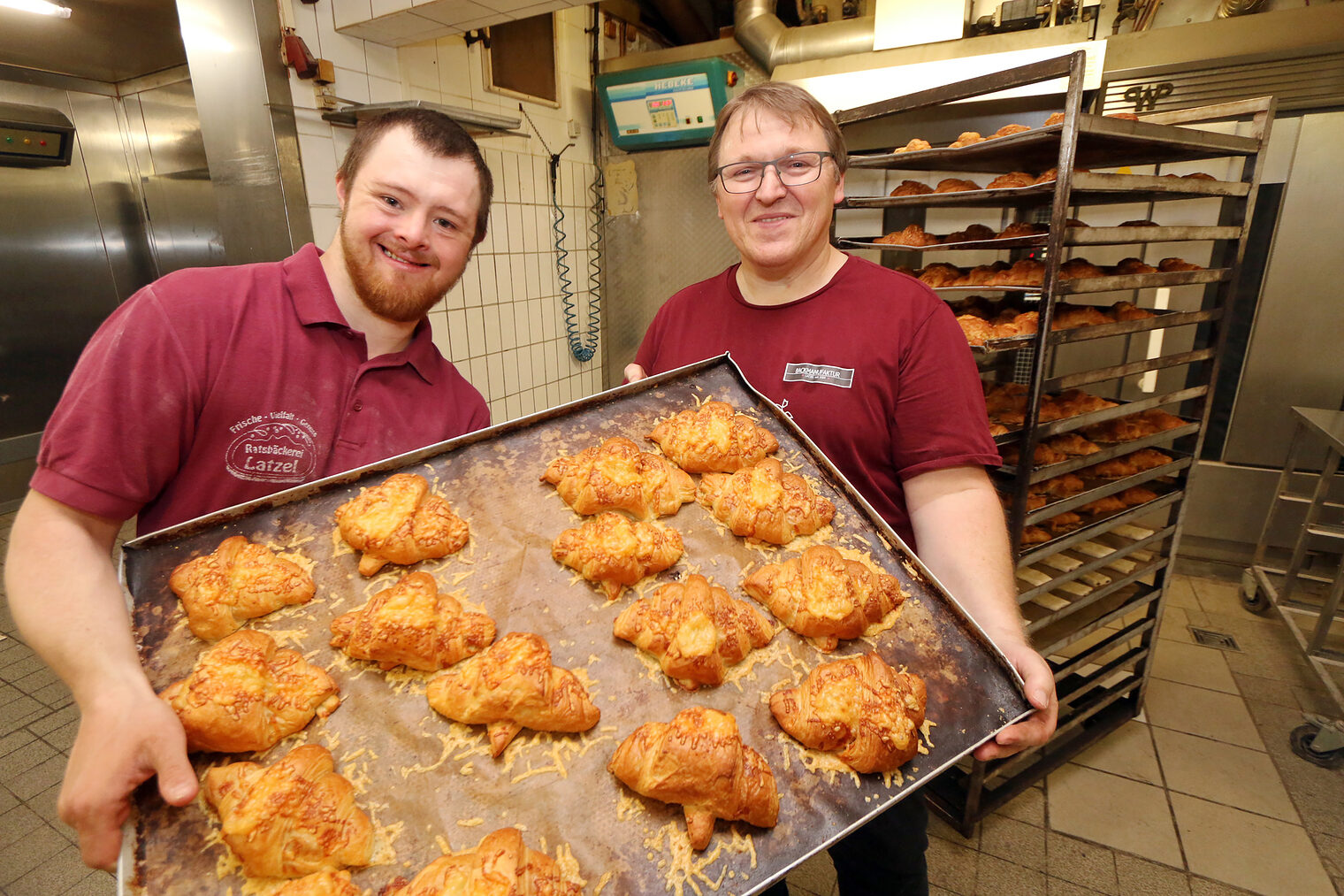 Julian Kruse und Konditormeister Rainer Knorr zeigen ein Blech mit Käse-Croissants in der Backstube der Ratsbäckerei Latzel.