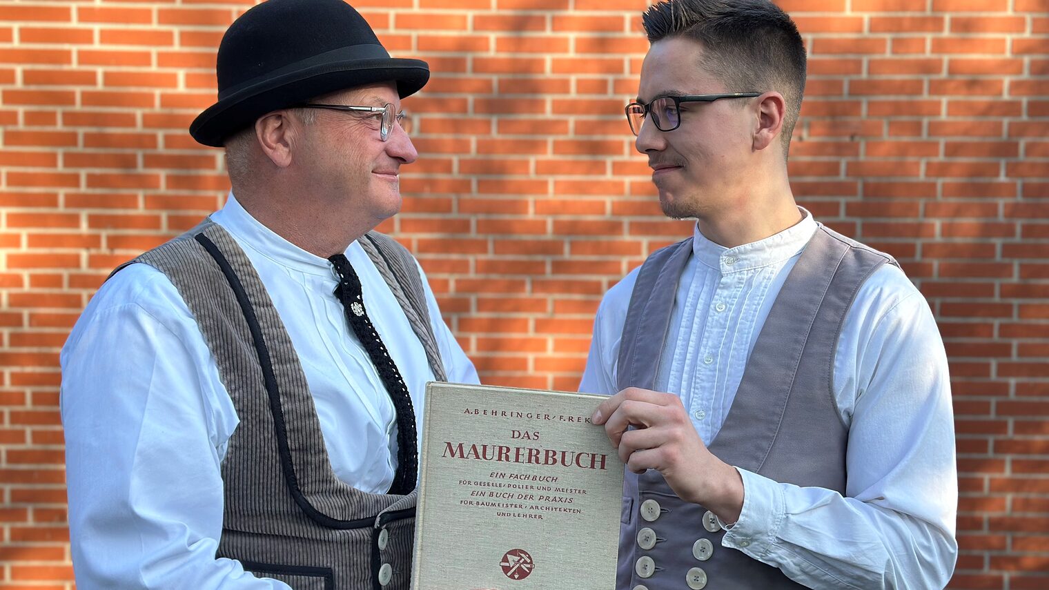 Maurermeister Velten Huhnholz übergibt an seinen Nachfolger Paul Sadowski das Maurerbuch.
