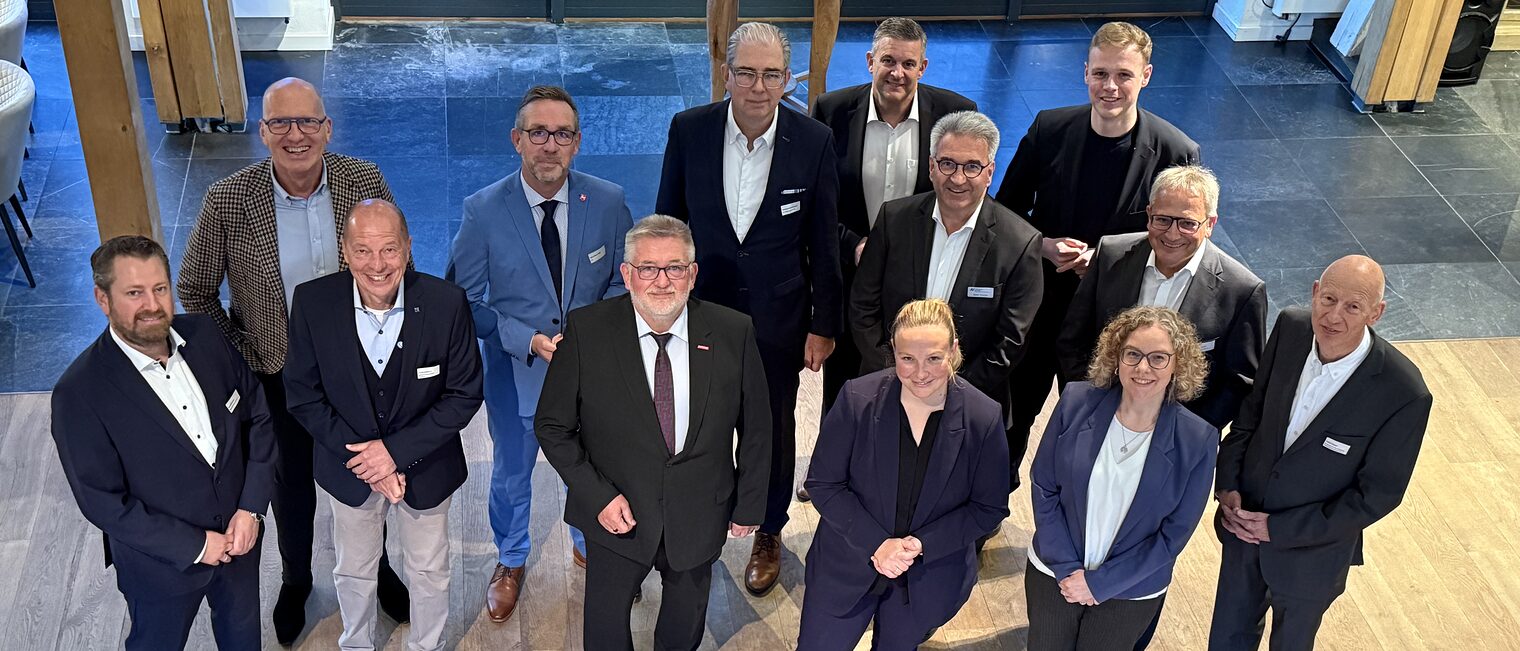 Austausch beim Parlamentarischen Abend der Wirtschaft 2025 Gruppenfoto von Teilnehmer:innen des Parlamentarischen Abends der Wirtschaft 2025 in Businesskleidung vor moderner Kulisse