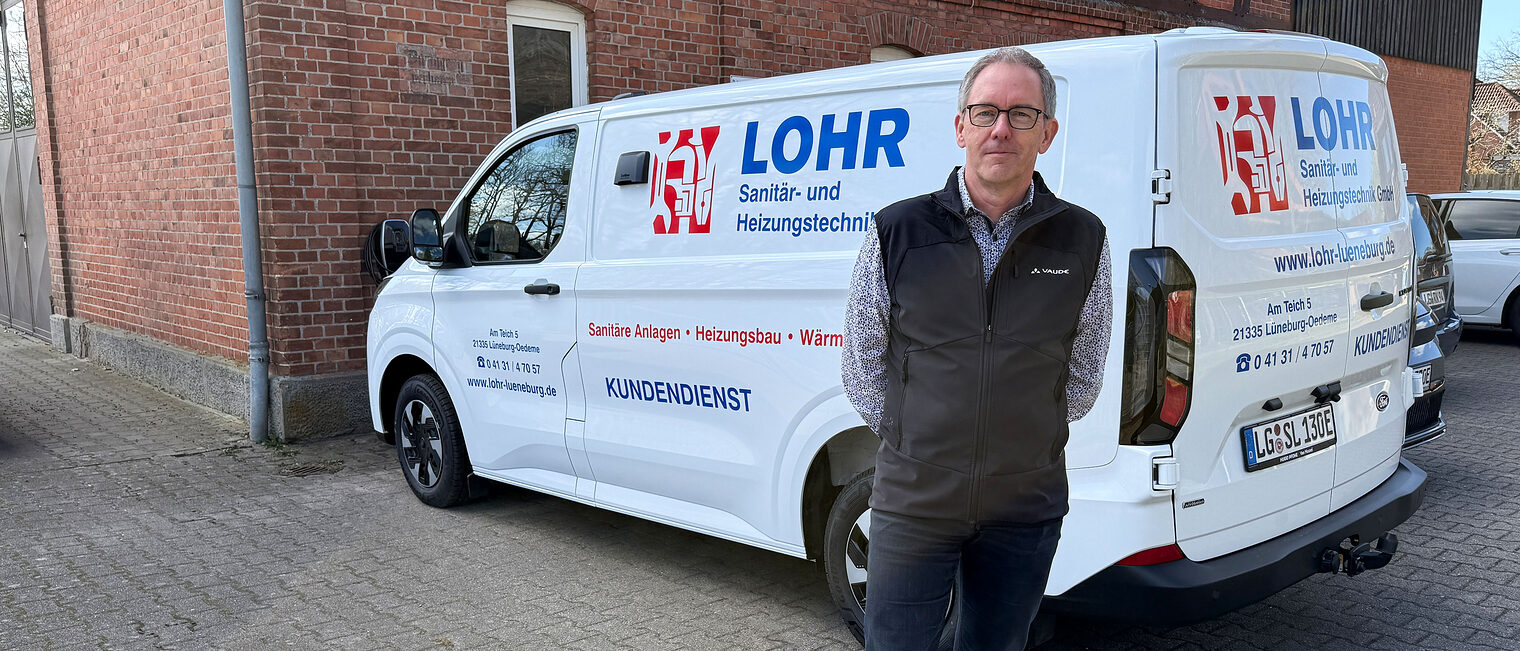 Sanitär- und Heizungstechniker Stefan Lohr als Lüneburg vor seinem Firmenfahrzeug mir "Lohr"-Folierung 