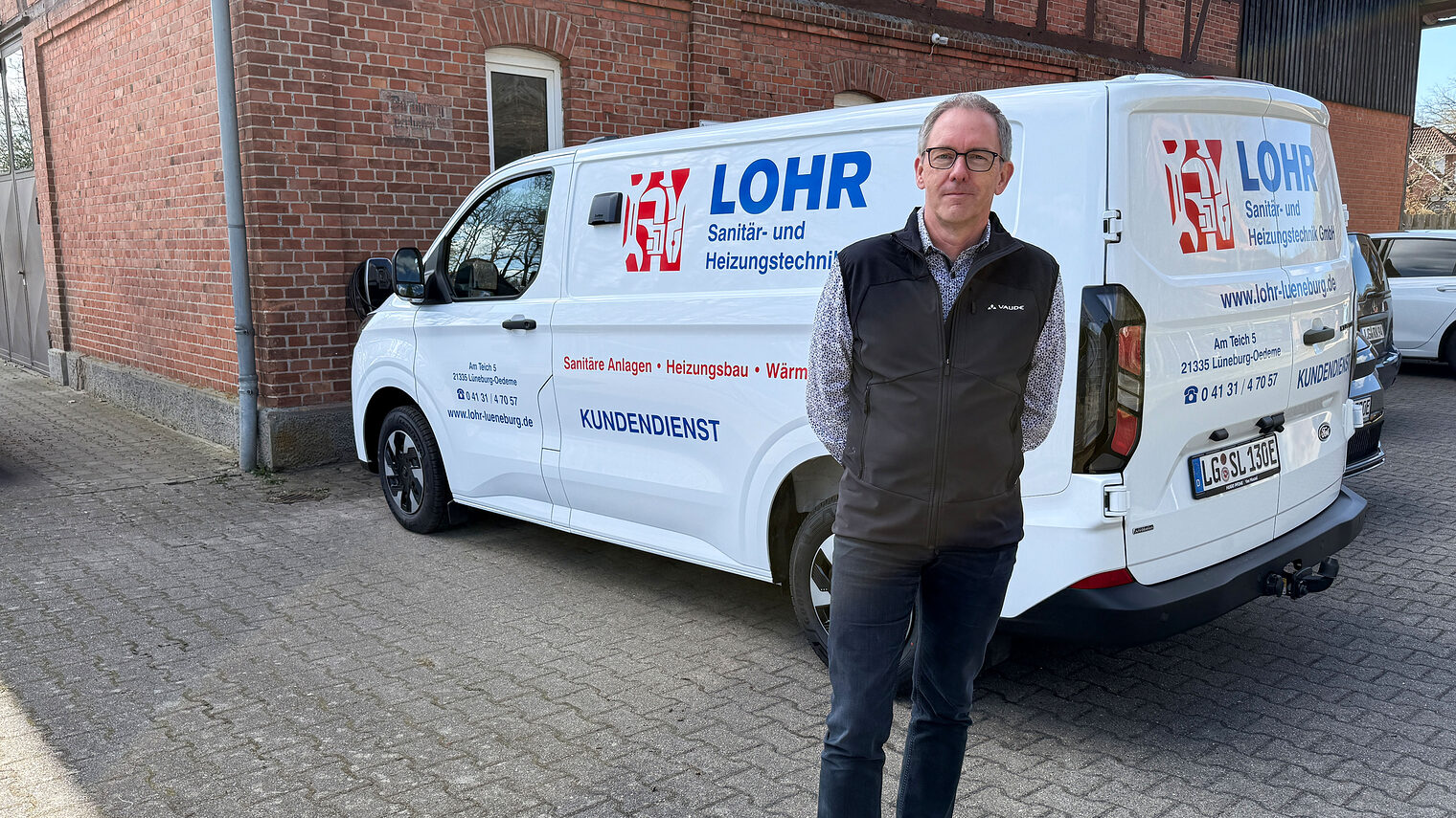 Sanitär- und Heizungstechniker Stefan Lohr als Lüneburg vor seinem Firmenfahrzeug mir "Lohr"-Folierung 