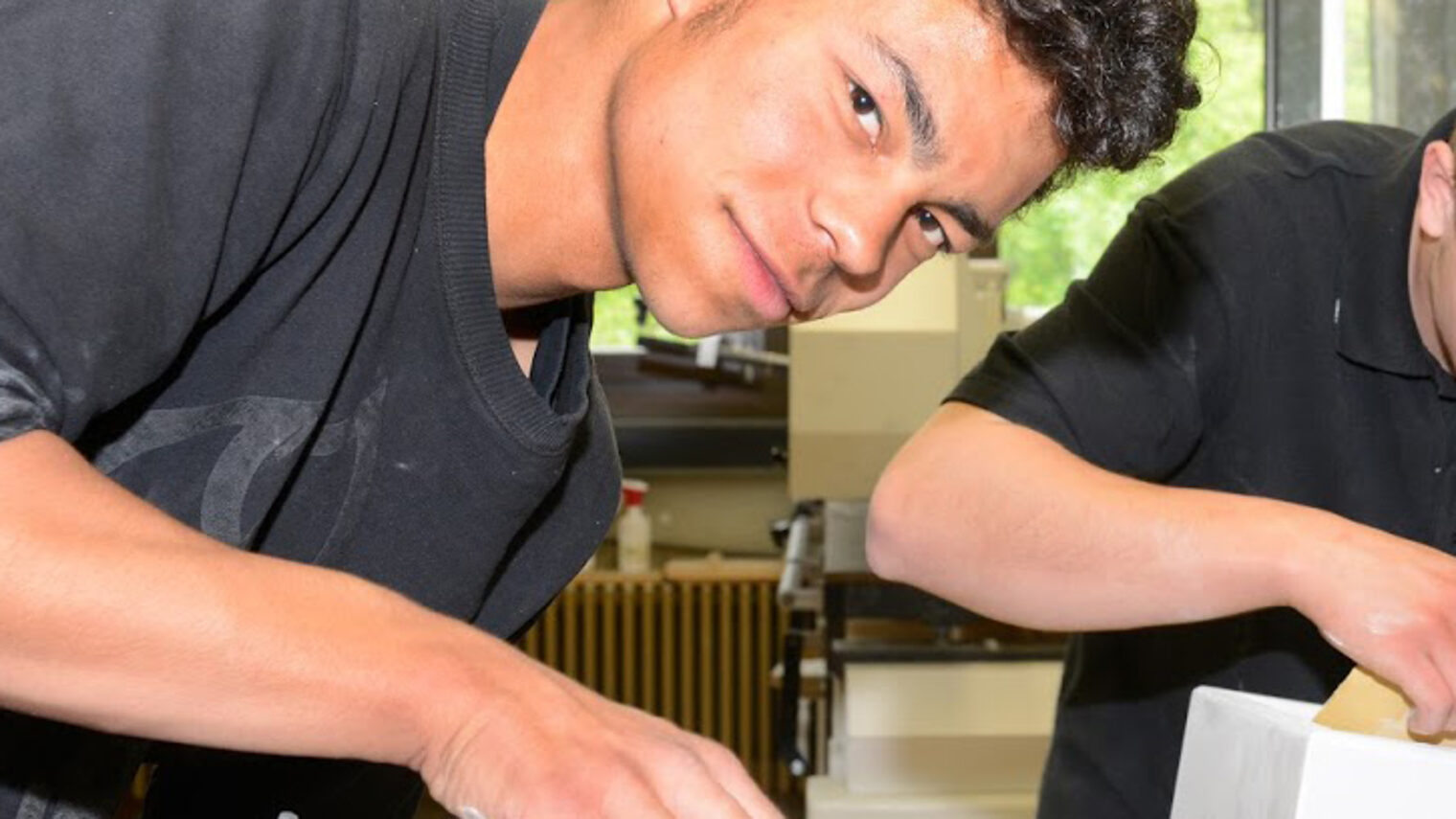Zwei Auszubildende arbeiten in der Tischlerwerkstatt.